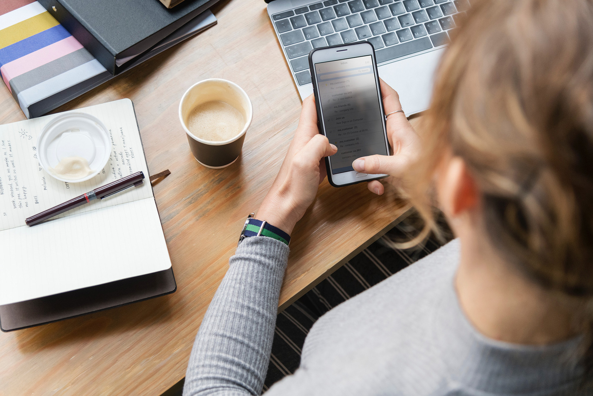 Person at desk using phone and laptop